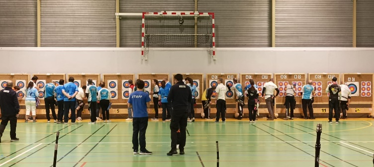 Des archers récupérant leur flèches sur des cibles, lors d'un concours en salle.